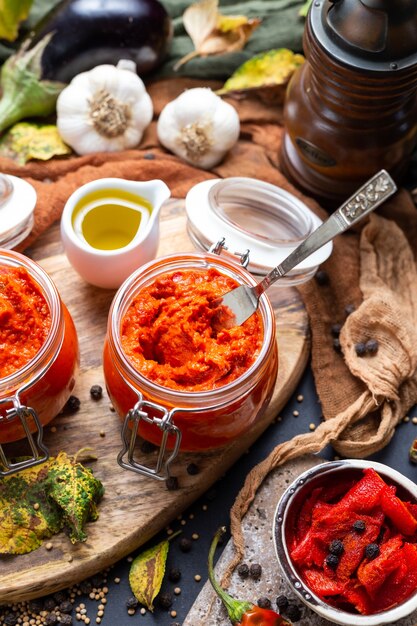 Close de ajvar cru na mesa com vegetais e molhos no fundo