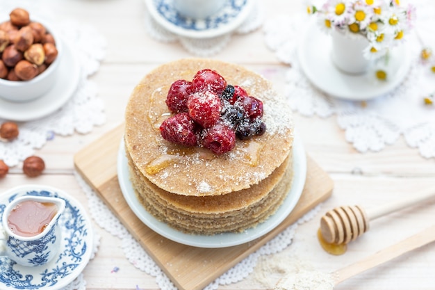 Close de ângulo alto de panquecas veganas cruas com mel e frutas vermelhas