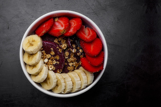 Close de ângulo alto de uma tigela branca com fatias de morango e banana