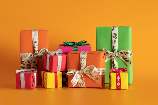 Close de caixas de presente multicoloridas em um fundo laranja, clima de Natal
