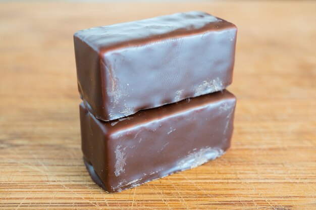 Close de dois blocos de chocolate empilhados em uma mesa de madeira