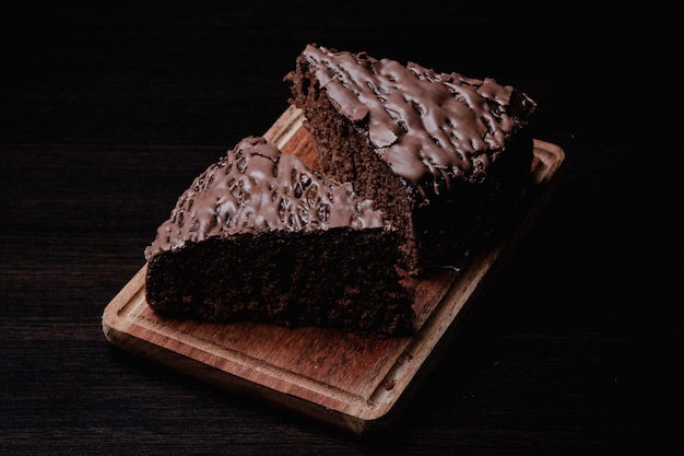 Close de dois pedaços de bolo de chocolate saboroso em uma placa de madeira