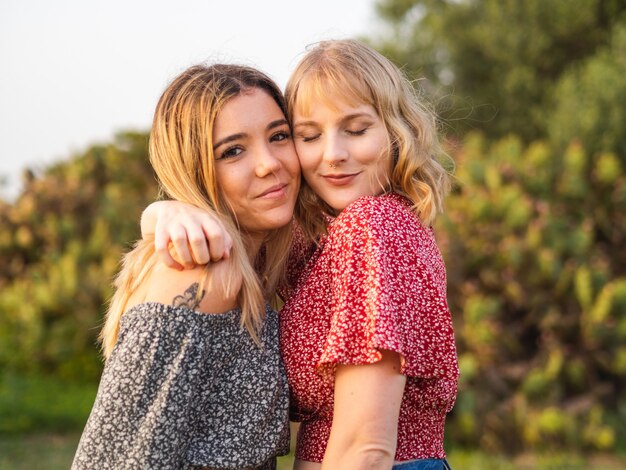 Close de duas amigas fofas se abraçando e posando no parque