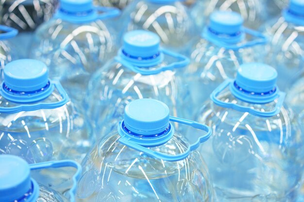 Close de garrafas plásticas de água potável de cinco litros, foco suave