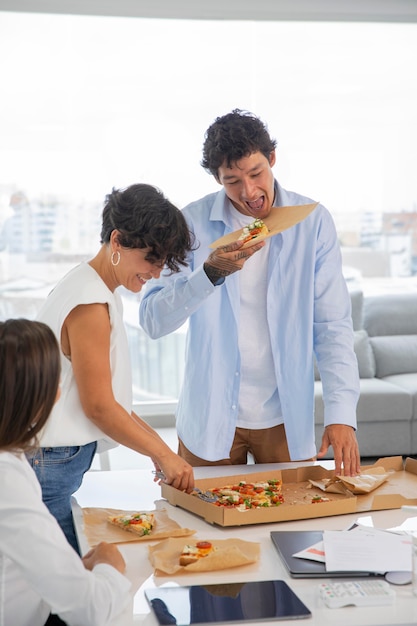 Close de pessoas comendo pizza no trabalho