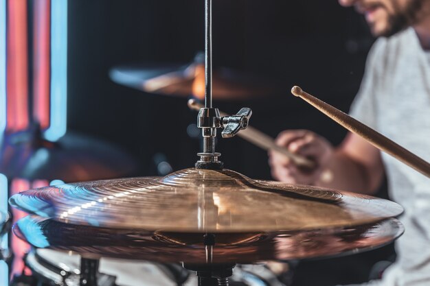 Close de um baterista tocando um prato de bateria, parte de uma bateria em uma tomada cortada.