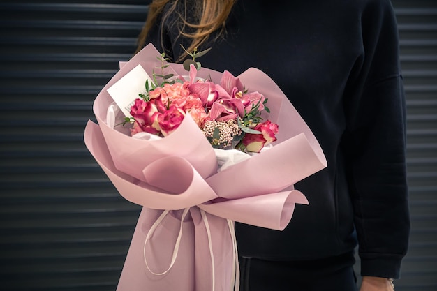 Close de um buquê de flores cor de rosa nas mãos femininas