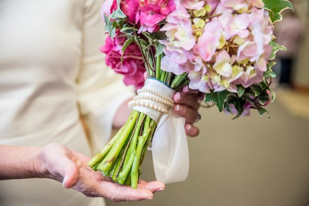 Close de um buquê de flores de noiva feito de várias flores em tons de rosa