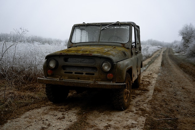 Close de um carro velho na estrada cercado por árvores de inverno