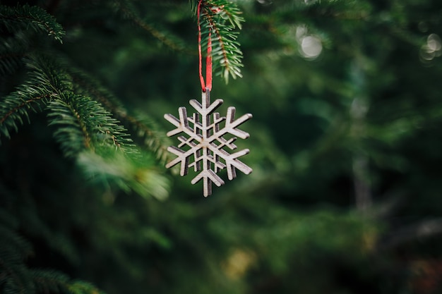 Close de um enfeite de Natal de madeira em forma de floco de neve em um pinheiro