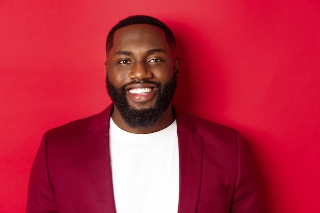 Close de um homem negro bonito e elegante usando blazer de festa, sorrindo feliz para a câmera