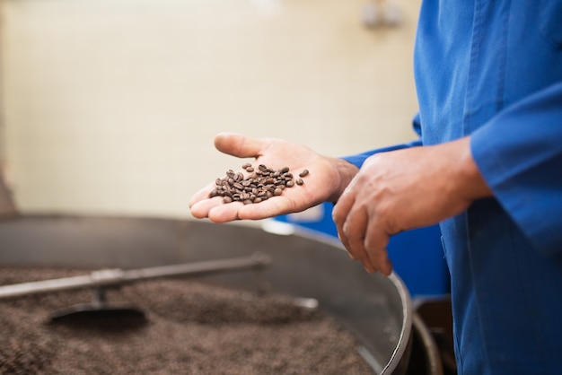 Close de um homem segurando grãos de café torrados