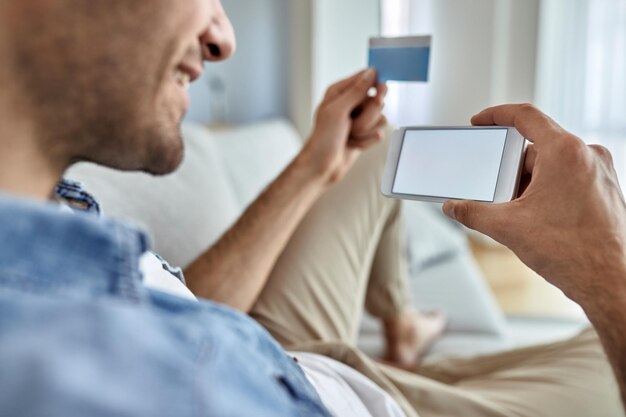 Close de um homem usando telefone inteligente e cartão de crédito enquanto verifica sua conta bancária online em casa Copiar espaço