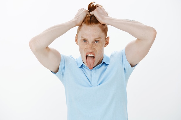 Foto grátis close de um ruivo bobo e engraçado bagunçando o cabelo e mostrando a língua