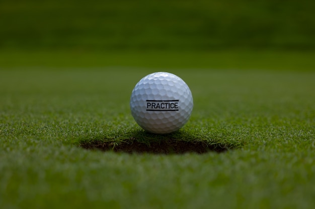 Close de um texto de prática escrito em uma bola de golfe no gramado sob a luz do sol