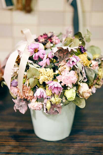 Close de um vaso com flores murchas em uma mesa de madeira