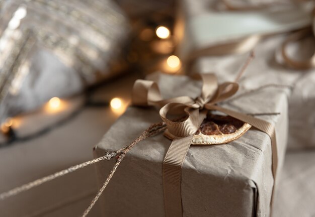 Close de uma caixa de presente de natal, decorada com flores secas e uma laranja seca, embrulhada em papel artesanal.