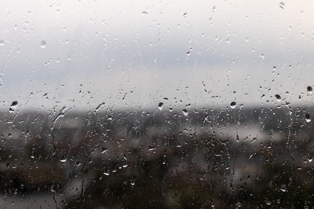 Close de uma janela em um dia chuvoso e sombrio, gotas de chuva rolando pela janela