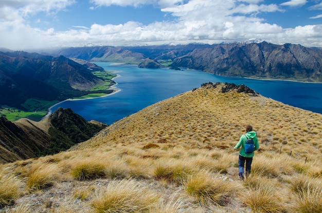 Close de uma mulher caminhando no Pico do Istmo e um lago na Nova Zelândia