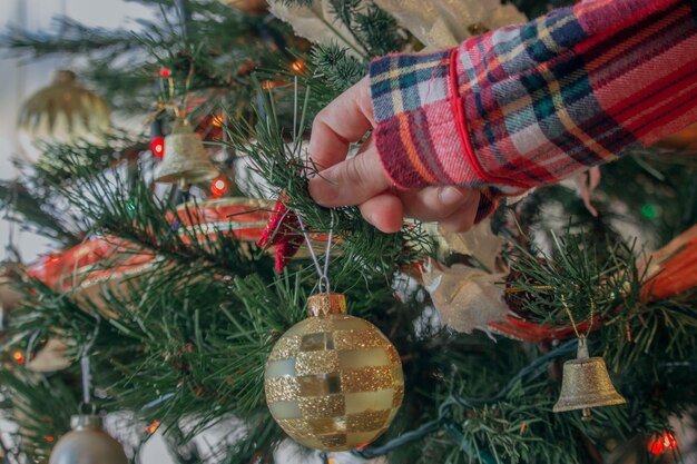 Close de uma mulher decorando uma árvore de Natal com bolas brilhantes