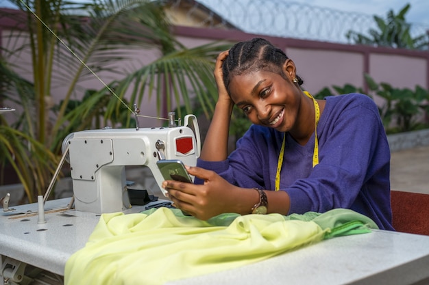 Foto grátis close de uma mulher negra sorrindo para o telefone com tecidos na frente dela