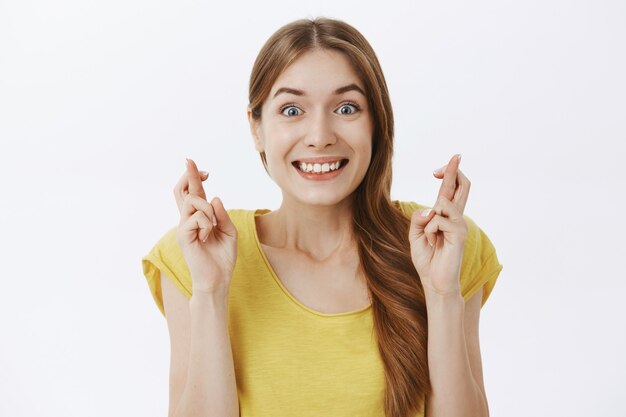 Close de uma mulher sorridente e esperançosa fazendo um desejo, antecipando uma boa notícia