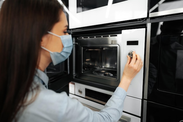 Foto grátis close de uma mulher verificando um novo forno de micro-ondas em um hipermercado