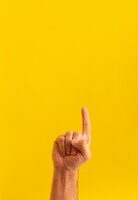 Foto grátis close de uma pessoa apontando para cima isolada em um fundo amarelo com espaço para texto