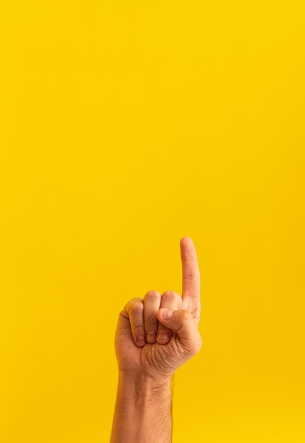 Close de uma pessoa apontando para cima isolada em um fundo amarelo com espaço para texto