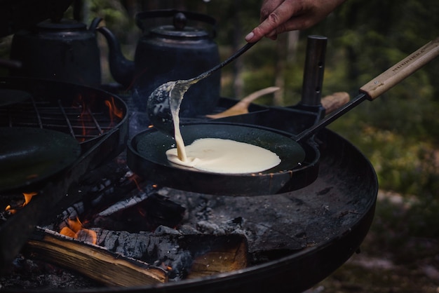 Close de uma pessoa cozinhando panquecas na fogueira ao ar livre