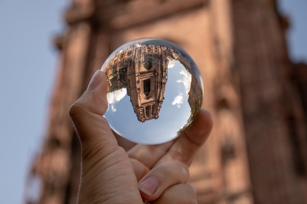 Close de uma pessoa segurando uma bola de cristal com o reflexo de edifícios históricos