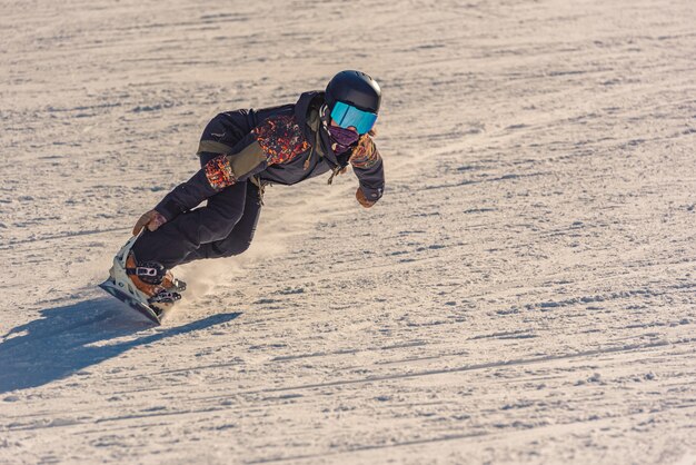 Close de uma snowboarder em movimento em uma prancha de snowboard em uma montanha