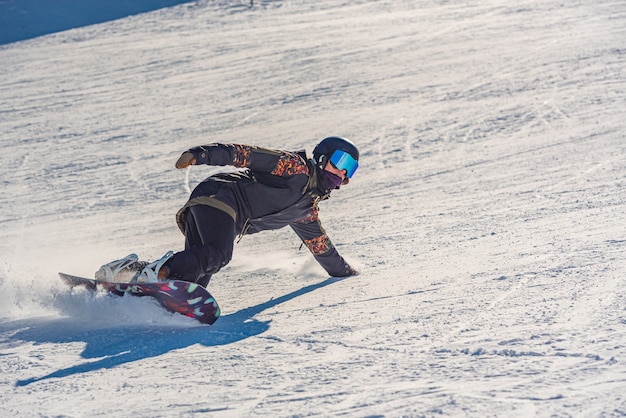 Close de uma snowboarder em movimento em uma prancha de snowboard em uma montanha