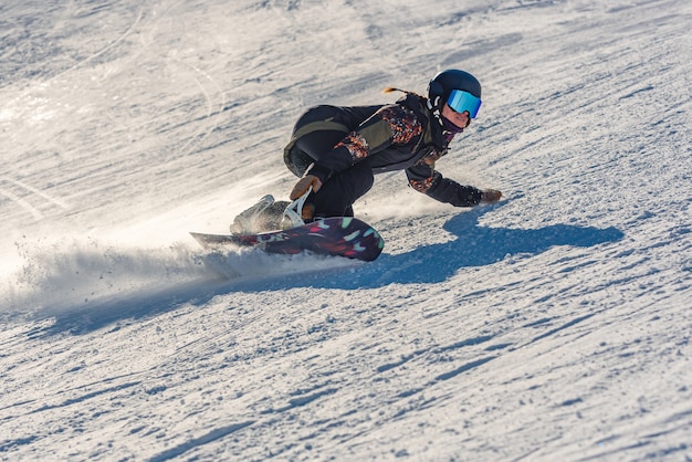 Close de uma snowboarder em movimento em uma prancha de snowboard em uma montanha