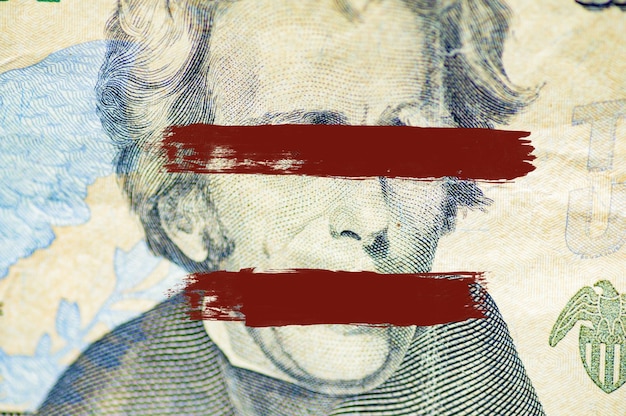 Close do rosto de Andrew Jackson na nota de um dólar com linhas pintadas sobre os olhos e a boca