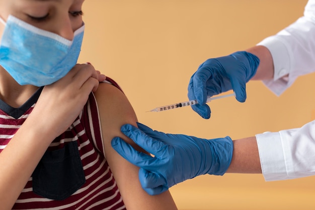Close garoto com máscara recebendo vacina