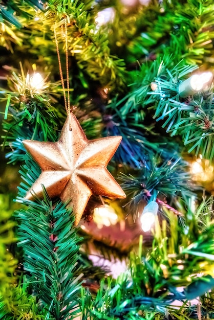 Close lindo de um enfeite de ouro em uma árvore de Natal com luzes