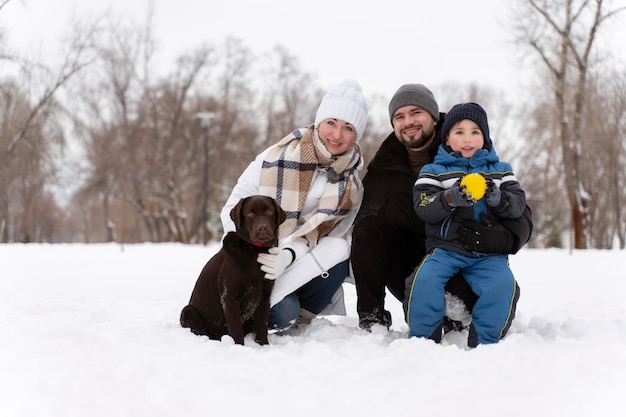 Foto grátis close na família feliz brincando na neve com o cachorro