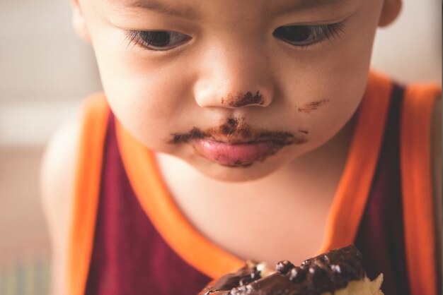 Close-up cara de garotinho faminto eaitng donut quente
