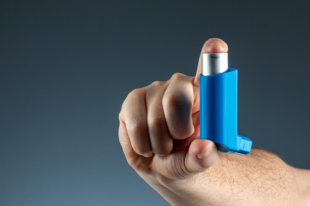 Close-up com um inalador de asma na mão masculina, ataque asmático. o conceito de tratamento da asma brônquica, tosse, alergias, dispnéia.