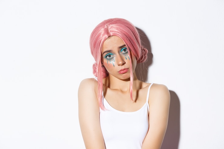 Foto grátis close-up da boba linda garota na peruca rosa, parecendo infeliz para a câmera, usando maquiagem e fantasia de halloween.