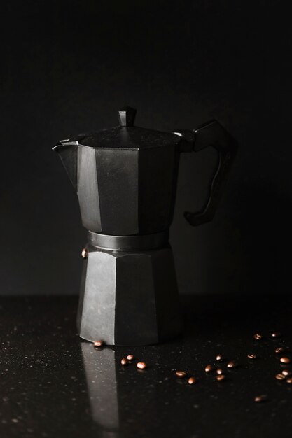 Close-up da cafeteira com grãos de café torrados em fundo preto
