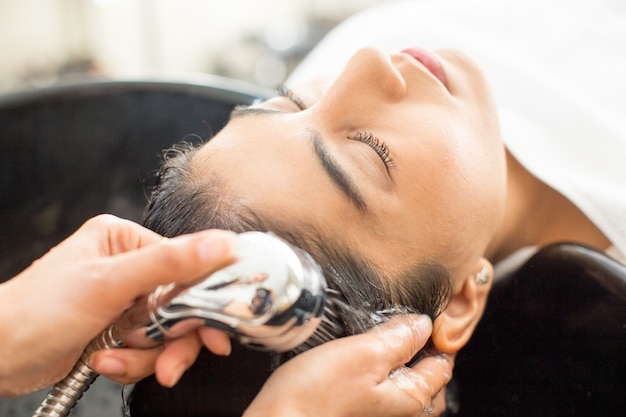 Close-up da jovem mulher relaxada no salão de cabeleireiro