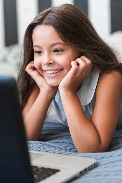 Close-up da linda garota sorridente, olhando para laptop