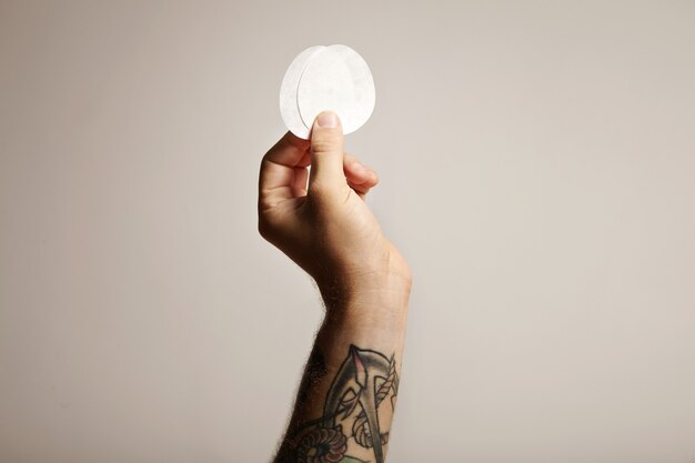 Close-up da mão de um homem tatuado segurando dois filtros de papel para a cafeteira não tradicional Aeropress