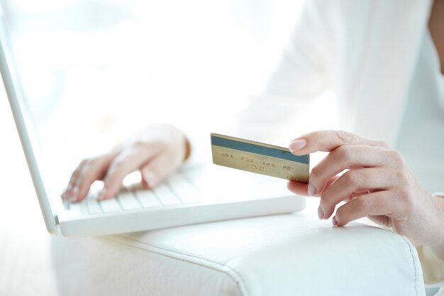 Close-up da mulher de compras on-line com cartão de crédito e laptop