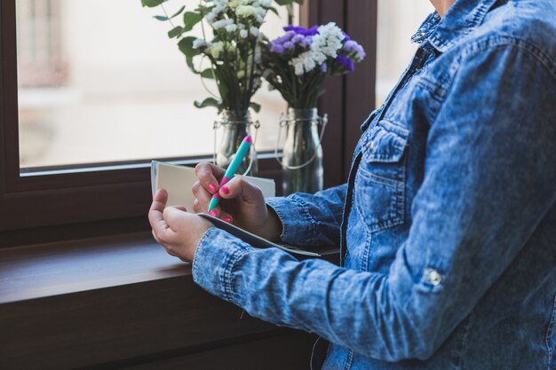 Foto grátis close-up da mulher no denim jaqueta escrito em um caderno