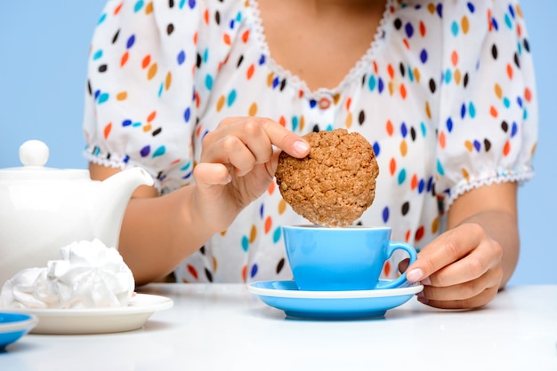 Close-up das mãos da mulher mergulhando biscoito no leite