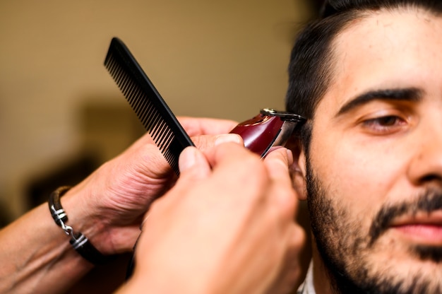 Close-up de barbeiro, dando ao cliente um corte de cabelo