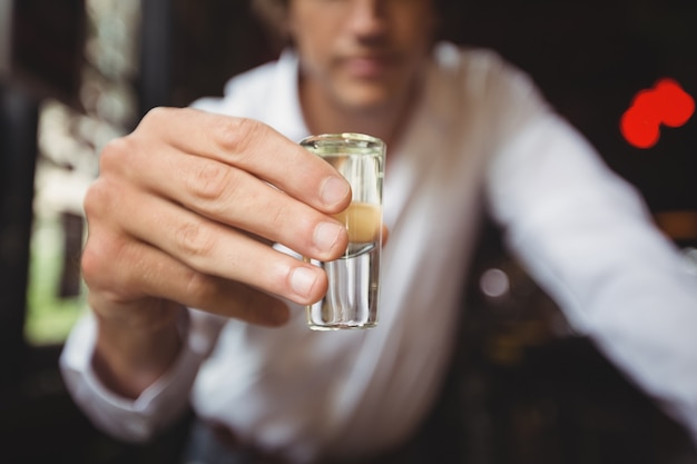 Foto grátis close-up de barman segurando copo de tequila no balcão de bar